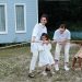 A happy family enjoys a game of tug of war in a grassy field by a house.