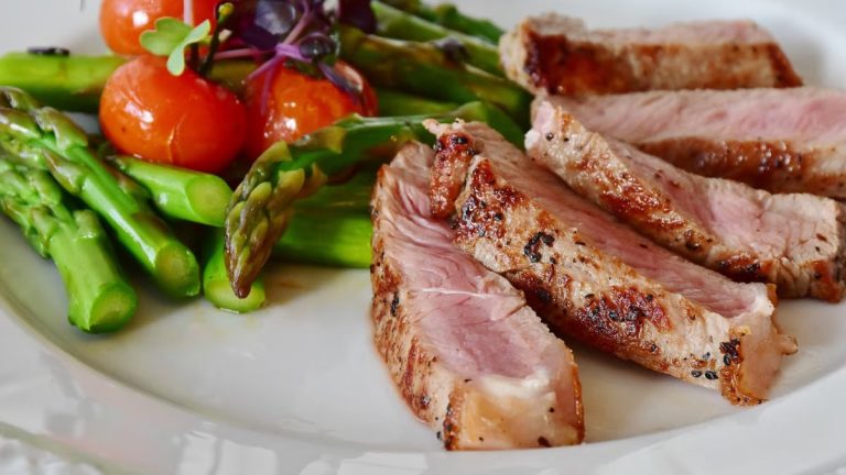Close-up of grilled steak slices with asparagus and cherry tomatoes, perfect for a healthy meal.